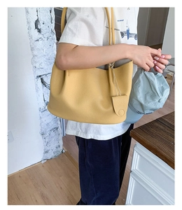 Detailansicht der gelben Totebag aus Leder mit Litschi-Maserung und modischem Anhänger