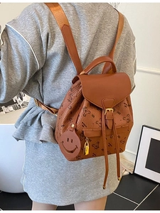 Brown leather backpack with bear print and cute charms worn by a model in a casual setting