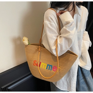 Detail view of woven summer tote bag with colorful embroidery and long yellow strap