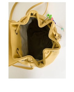Close-up of yellow drawstring bucket bag showing pebble leather texture and interior pocket