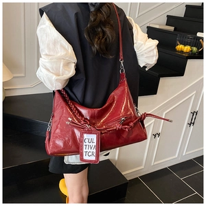 Detail of red glossy tote bag featuring a woven handle and textured faux leather finish