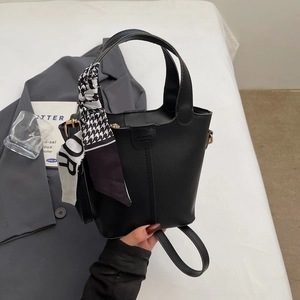 Close-up of black bucket bag with leather texture and houndstooth scarf detail