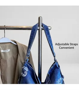 Detail of blue denim shoulder bag with distressed finish and adjustable metal strap buckle