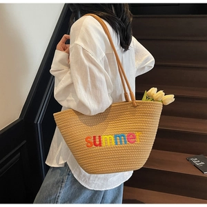 Detail of hand-woven straw tote bag with colorful summer embroidery and leather straps