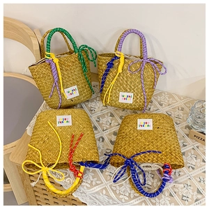 Detail of woven straw tote bag featuring colorful cotton rope handles and drawstring liner