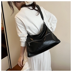 Detail view of high-gloss black tote bag with premium pleated leather texture and silver zipper