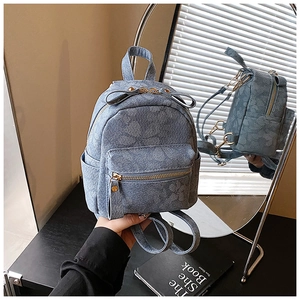 Detail of blue floral embossed mini backpack with gold zippers and stylish metal hardware