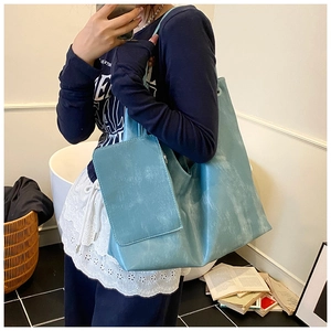 Detail view of large light blue tote bag with stone-washed texture and matching small pouch