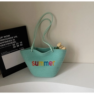 Detail of mint green woven tote bag featuring colorful summer embroidery and wavy top edge
