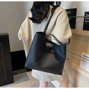 Close-up of black tote bag with embossed letters, litchi texture leather, and sturdy stitching