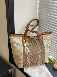 Large woven straw beach tote bag with leather handles and yellow tassel charm