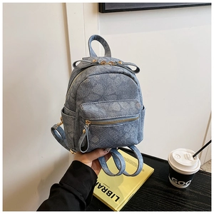 Detail of mini blue denim backpack with gold zipper, bow design and adjustable straps