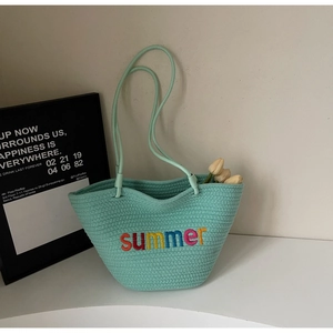 Close-up of mint green woven tote bag with colorful summer embroidery and slim handles