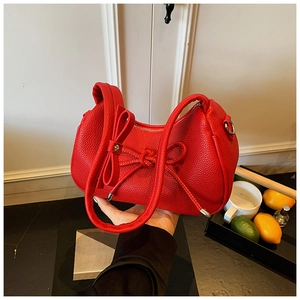 Detail showing red litchi grain texture and 3D bow decoration on the shoulder bag