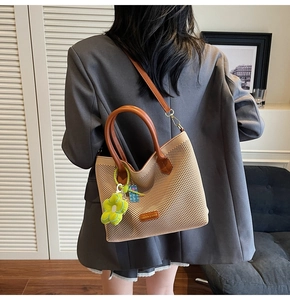 Détail du sac cabas tissé beige avec lanières en cuir brun et breloque fleurie