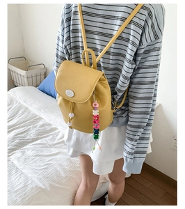 Detail view of yellow faux leather mini backpack with drawstring and colorful bead charm