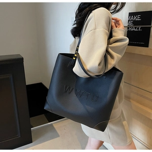 Detail view of large black tote bag featuring embossed WWTU lettering and pebbled leather