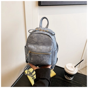 Detail view of denim blue mini backpack with floral pattern and front zipper pocket