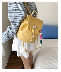 Detail view of yellow lychee leather backpack with drawstrings and tassel charm