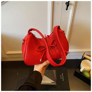 Detail of red lychee textured leather handbag with elegant bow drawstring design