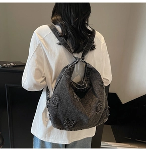 Rear view of a vintage dark grey denim tote bag with distressed details and embroidered letters