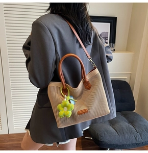Détail du sac cabas en maille avec bandoulière en cuir et breloque fleur verte pour femme
