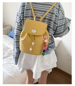 Detail of yellow mini backpack featuring litchi grain leather and cute bunny emblem