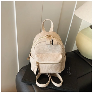 Detail view of cream mini backpack with textured finish on a decorative photography book