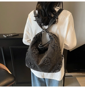 Back view of a washed denim backpack with frayed letter patches on a female model