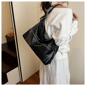 Close-up of black pleated faux leather shoulder bag with metallic silver zipper detail