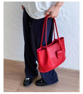 Detailansicht einer großen roten Tote-Bag aus genarbtem Leder mit dekorativem Anhänger
