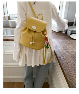 Detail of yellow mini PU leather backpack with drawstring closure and beaded charm
