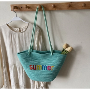 Detail of mint green woven tote bag with colorful summer embroidery and long straps