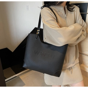 Detail of the black large tote bag showing textured pebble leather and embossed WWTU logo