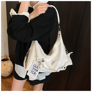 Detail of white glossy hobo bag with woven strap, silver hardware and side pocket