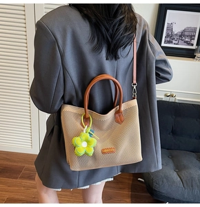 Sac fourre-tout en résille avec breloque fleur verte porté par un mannequin de bureau