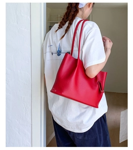Detailansicht einer roten Ledershopper-Tasche, getragen von einem Model im Innenbereich