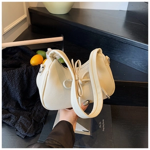 Detail of cream white pebbled leather shoulder bag featuring a stylish bow and thick strap