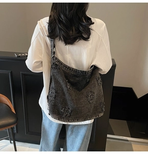 Detail of vintage charcoal grey denim tote bag with frayed letter patches and metal buckles