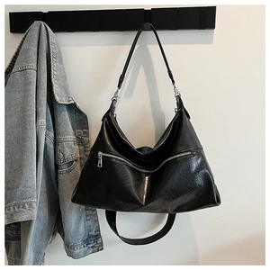 Detail of black glossy leather tote bag with silver zipper and adjustable strap