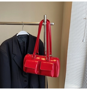 Detail of red glossy bowling bag featuring dual front pockets and sleek long straps