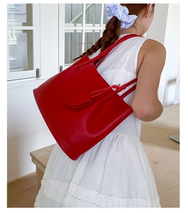 Detail der roten Tote Bag aus genarbtem Leder mit Blattanhänger am Schultergurt