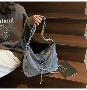 Détail du sac hobo en jean bleu avec laçage décoratif et fermeture éclair métallique