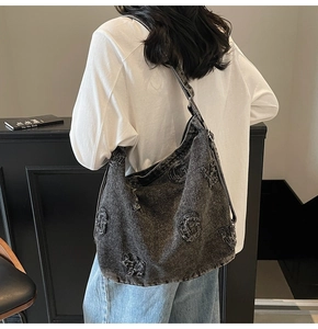 Detail of vintage washed denim hobo bag with G-letter embroidery and adjustable strap