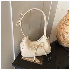 Detail of cream bow shoulder bag with lychee grain texture and minimalist aesthetic