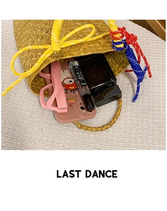 Detail of woven straw handbag showing colorful rope accents and interior storage capacity