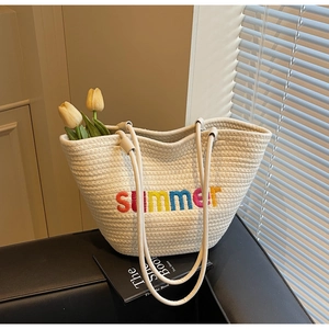 Close-up of cream woven tote bag featuring colorful summer embroidery and sturdy rope strap
