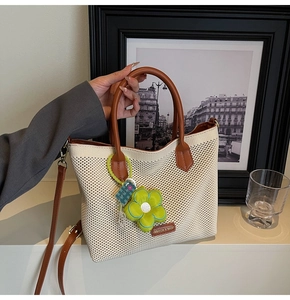 Détail du sac cabas tissé avec poignées en cuir et breloque tournesol vert
