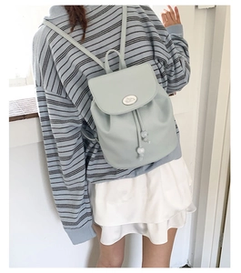 Detail view of a mint green pebbled leather mini backpack on a person wearing a striped shirt