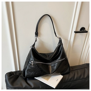 Detail of black wrinkled patent leather tote with metal zipper and modern shoulder strap